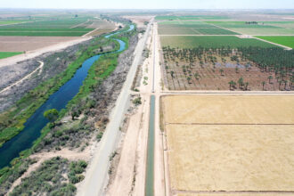 An irrigation ditch, center, carries river water toward Quechan tribal land along the long-depleted Colorado River, left, as it flows between California, right, and Arizona, on May 26, 2023 near Winterhaven, California. The Quechan Tribe of the Fort Yuma Indian Reservation and the neighboring Bard Water District currently have voluntary seasonal fallowing programs which compensate farmers to not grow crops on some of their fields to boost water levels at Lake Mead. Credit: Mario Tama/Getty Images