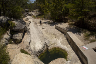 The water in Jacob's Well is at its lowest level in memory, in August 2023. Usually, it gushes into the bed of Cypress Creek, which is currently dry. Credit: Dylan Baddour/Inside Climate News.