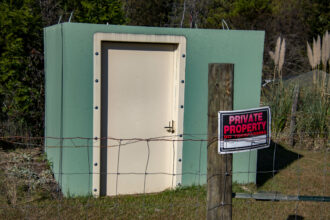 A newly constructed fence bearing a "no trespassing" sign stands in front of Sandy Pouncey's storm shelter. Credit: Lee Hedgepeth/Inside Climate News