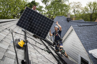 Pete Southerton (left) and Tom Bradshaw, of solar energy contractor Certasun, install solar panels on a Chicago home on May 17, 2021. Credit: Ashlee Rezin Garcia/Sun-Times