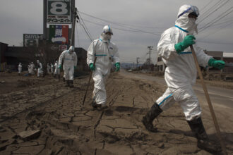 Japanese Police wearing protective suits search for tsunami victims about 12 miles away from Fukushima Nuclear Power Plant on April 7, 2011 in Minamisoma, Fukushima Prefecture, Japan. Credit: Athit Perawongmetha/Getty Images
