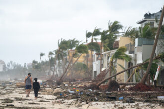People walk along the beach looking at property damaged by Hurricane Ian on September 29, 2022 in Bonita Springs, Florida. The storm made a U.S. landfall on Cayo Costa, Florida, and brought high winds, storm surges, and rain to the area causing severe damage. Credit: Sean Rayford/Getty Images