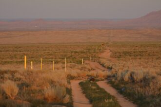 Dusk falls on the existing Southern Trails natural gas pipeline owned by the Navajo Nation as it passes through empty land west of Shiprock, New Mexico. Locals say someone showed up and put in the yellow markers a few months earlier. Credit: Jerry Redfern.