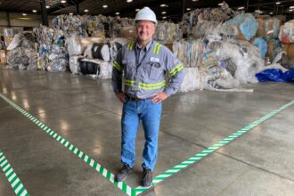 Jay Schabel, president of the plastics division at Brightmark, stands amid what he described as 900 tons of waste plastic at the company's new plant in northeast Indiana at the end of July. The plant is designed to turn plastic waste into diesel fuel, naphtha and wax. Credit: James Bruggers