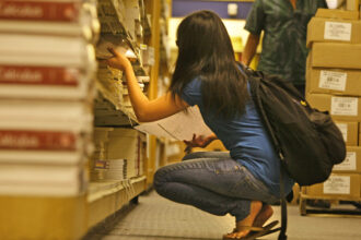 A student shuffles through a stack of used books at the U.C. Irvine bookstore on July 30, 2008. Credit: Don Bartletti/Los Angeles Times via Getty Images