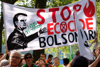 Activists hold up a banner of Jair Bolsonaro as they gather in front of the Brazilian Embassy during a demonstration organized by Extinction Rebellion activists on Aug. 26, 2019 in Brussels, Belgium. Credit: Thierry Monasse/Getty Images